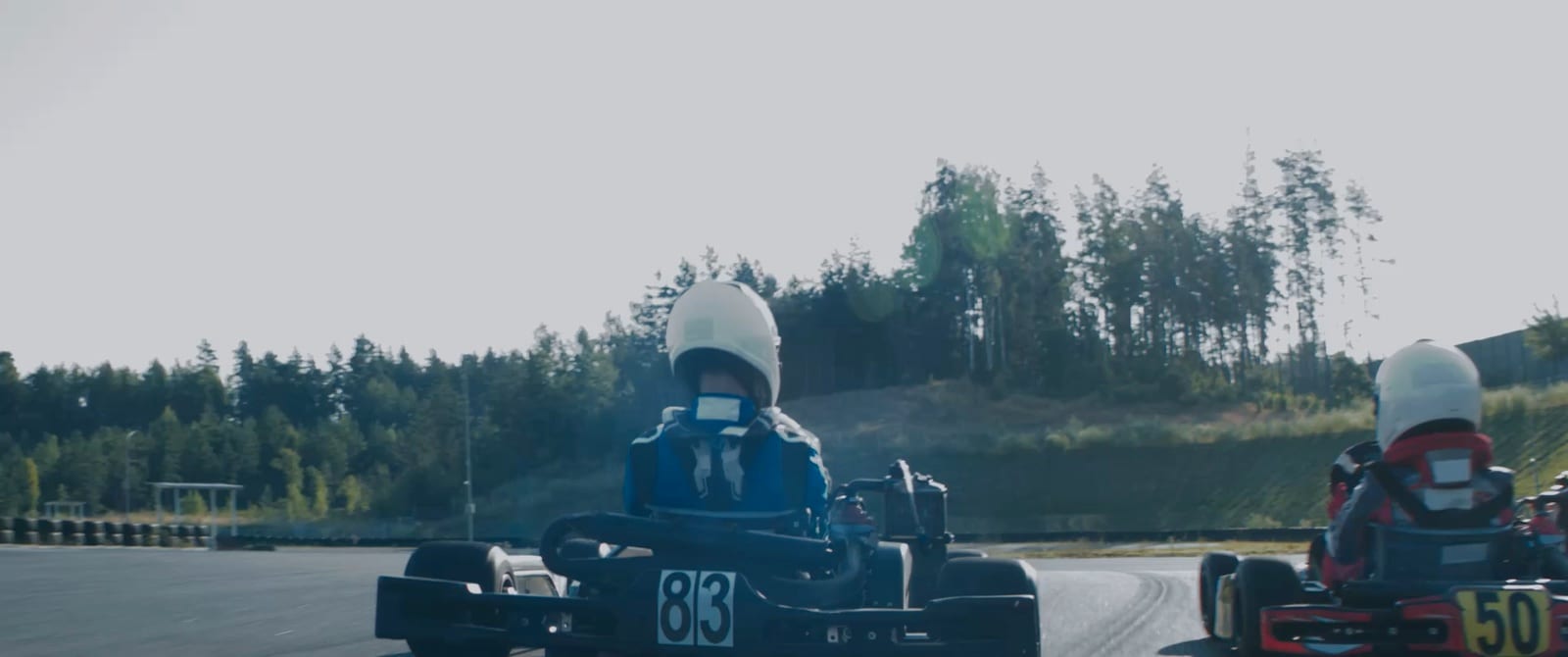 A kart at racing speed on circuit, tyre barriers behind